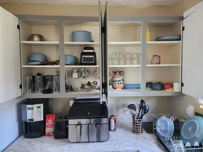a kitchen with white cabinets with dishes and utensils at Cozy 3-Bedroom Haven, Private Pool & Parking ! in Longueuil