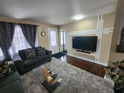 a living room with a couch and a flat screen tv at Cozy 3-Bedroom Haven, Private Pool & Parking ! in Longueuil