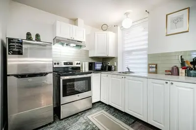 a kitchen with white cabinets and stainless steel appliances at Bienvenue dans votre havre de paix à Griffintown in Montréal