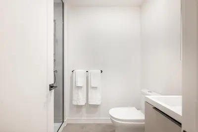 a white bathroom with a toilet and a sink at Le Mont Apartments in Montréal