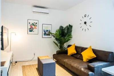 a living room with a brown couch and a clock on the wall at Castle Lofts Apartments in Montréal