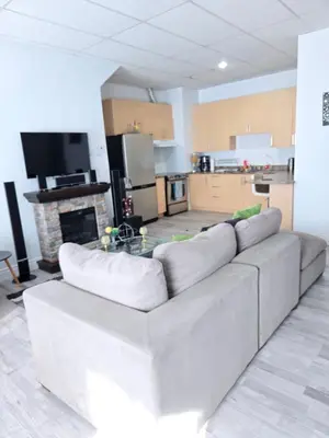 a living room with a couch and a kitchen at SylverPrud in Beauceville