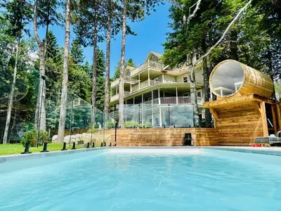 a house with a swimming pool in front of a building at Estello Suites & Spa in Lac-Mégantic