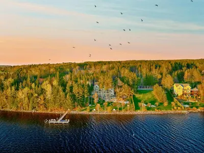 an island in the water with a house and a boat at Estello Suites & Spa in Lac-Mégantic