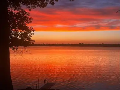 a sunset over a large body of water at Sunset Heaven - Modern Lake House with Spa in Venise-en-Québec