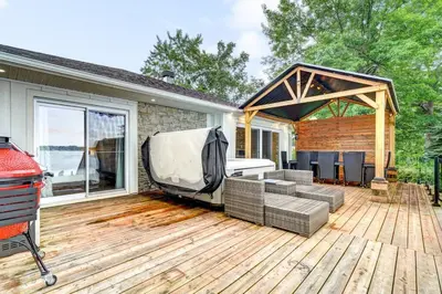 a covered deck with a grill and a grill at Sunset Heaven - Modern Lake House with Spa in Venise-en-Québec