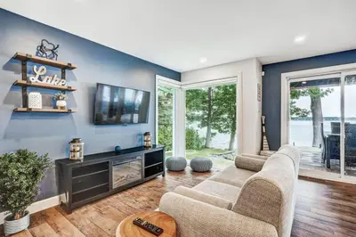 a living room with a couch and a tv at Sunset Heaven - Modern Lake House with Spa in Venise-en-Québec