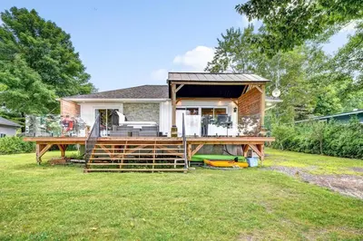a house with a large deck in the yard at Sunset Heaven - Modern Lake House with Spa in Venise-en-Québec