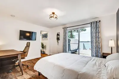 a bedroom with a bed and a desk and a window at Sunset Heaven - Modern Lake House with Spa in Venise-en-Québec