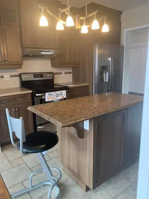 a kitchen with a counter and a bar with a chair at Appartment with Hot Tub and Backyard and Free Parking in Saint-Hyacinthe
