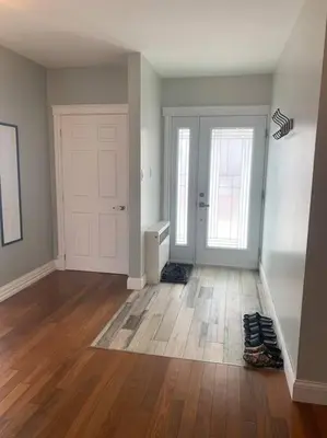 an empty room with a white door and wooden floors at Appartment with Hot Tub and Backyard and Free Parking in Saint-Hyacinthe