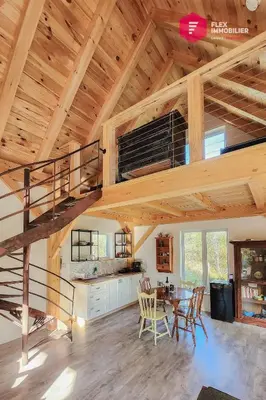 a kitchen and dining room with a spiral staircase in a house at L'Ermite - Rustique Écoresponsable Dans la nature in Notre-Dame-Des-Bois