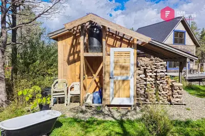 a small wooden cabin with a tub and a stack of logs at L'Ermite - Rustique Écoresponsable Dans la nature in Notre-Dame-Des-Bois