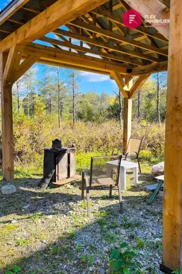 a wooden pavilion with two chairs and a stove at Le Pèlerin - Rustique Écoresponsable En nature in Notre-Dame-Des-Bois