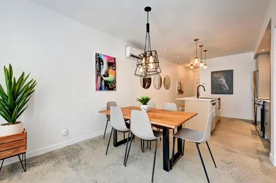a dining room with a wooden table and white chairs at Élégant 2ch 2sdb Beau Quartier de Montréal présenté par TripMontreal IV in Montréal