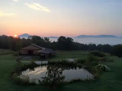 a house in the middle of a field with a pond at Spacious luxurious Villa, bright cottage, pool, Jacuzzi, sauna, nature in Mansonville
