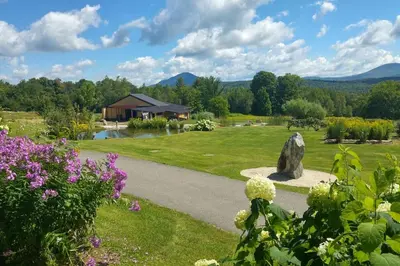 a garden with flowers and a building in the background at Spacious luxurious Villa, bright cottage, pool, Jacuzzi, sauna, nature in Mansonville