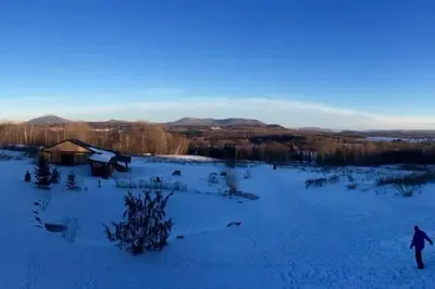 a person walking through a snow covered field at Spacious luxurious Villa, bright cottage, pool, Jacuzzi, sauna, nature in Mansonville