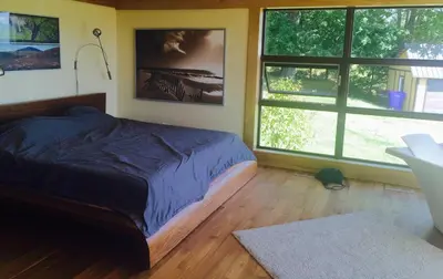 a bedroom with a bed and two large windows at Spacious luxurious Villa, bright cottage, pool, Jacuzzi, sauna, nature in Mansonville