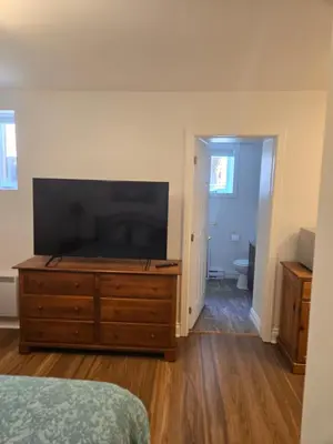 a bedroom with a large flat screen tv on a dresser at Doux cocon in Saint-Jean-sur-Richelieu