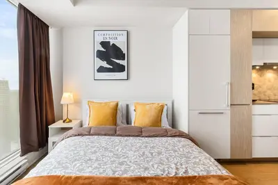 a white bedroom with a large bed and a window at Luxury Apartments with View & Indoor Heated Pool in Montréal