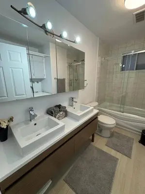a bathroom with two sinks and a toilet and a mirror at Ste-Rose 2 bedroom apt in Laval