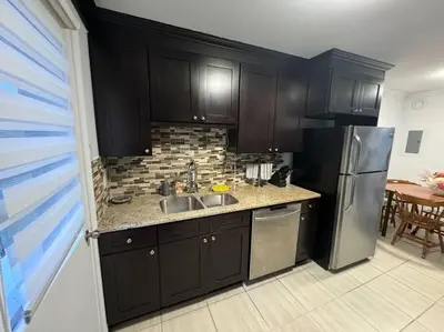 a kitchen with black cabinets and a stainless steel refrigerator at Ste-Rose 2 bedroom apt in Laval