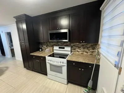 a kitchen with black cabinets and a white stove top oven at Ste-Rose 2 bedroom apt in Laval