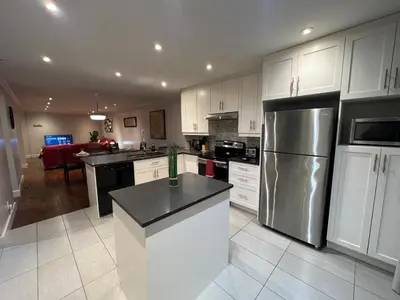 a kitchen with white cabinets and a stainless steel refrigerator at Amazing 3-Bedrooms in Rosemont - Montreal in Montréal