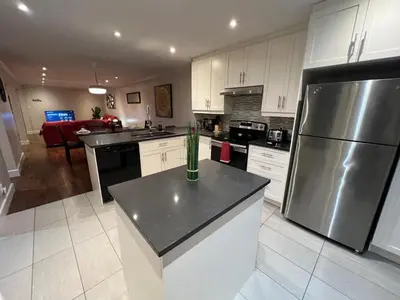 a kitchen with white cabinets and a stainless steel refrigerator at Amazing 3-Bedrooms in Rosemont - Montreal in Montréal