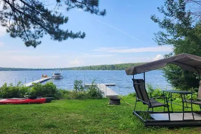 a table and a chair and a boat on a lake at Petit Elgin, quai Bord de l'eau, foyer, SPA in Stratford