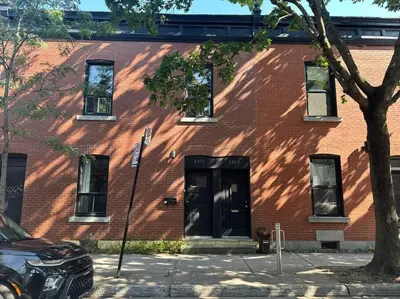 a red brick building with a door and a tree at 3-Bedroom Apt - Low monthly rate - Le Plateau in Montréal