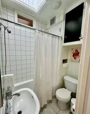 a white bathroom with a toilet and a sink at 3-Bedroom Apt - Low monthly rate - Le Plateau in Montréal