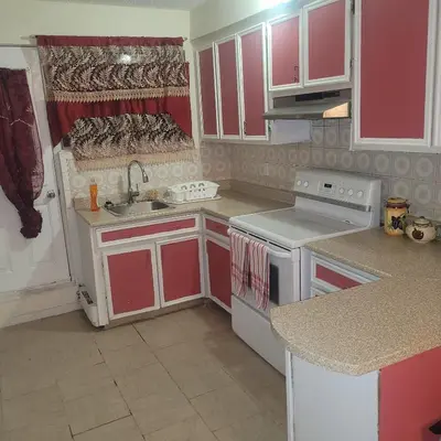 a kitchen with red and white cabinets and a sink at Chambre privée avec clefs intime et privée in Montréal