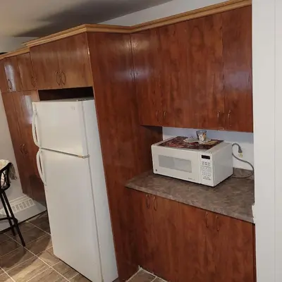 a kitchen with a white microwave and a refrigerator at Chambre vu à couper le souffle in Montréal