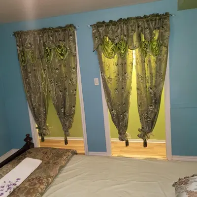 a bedroom with a bed and two windows with curtains at Chambre vu à couper le souffle in Montréal