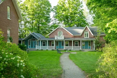 an old house with a porch and a yard at Manoir Sweetsburg in Cowansville