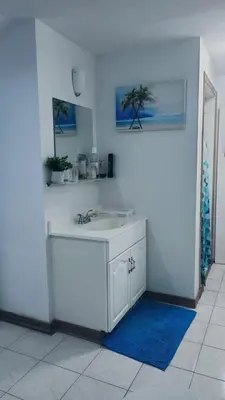 a white kitchen with a sink and a blue rug at CosyRoom in Brossard