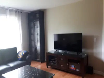 a living room with a flat screen tv on a entertainment center at Maison aux Mésanges in Waterloo