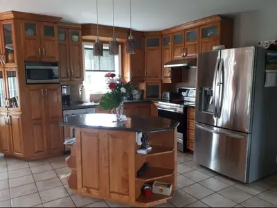 a kitchen with wooden cabinets and a stainless steel refrigerator at Maison aux Mésanges in Waterloo