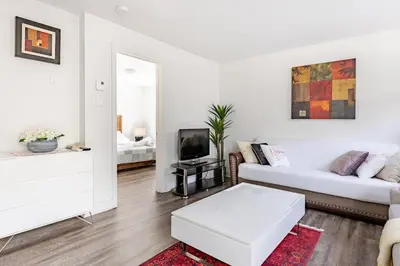 a white living room with a couch and a tv at Logement neuf, spacieux in Longueuil