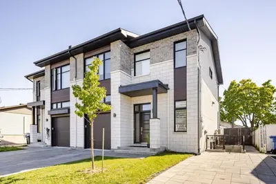 a house with a tree in front of it at Logement neuf, spacieux in Longueuil