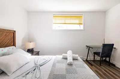 a white bedroom with a bed and a desk at Logement neuf, spacieux in Longueuil