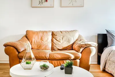 a brown leather couch in a living room with a table at Lumière et Propreté à McGill parking gratuit in Montréal