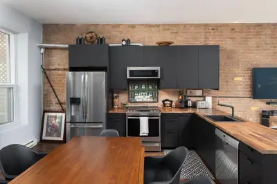 a kitchen with black cabinets and a wooden table at Two bedroom duplex in Plateau Mont-Royal district in Montréal