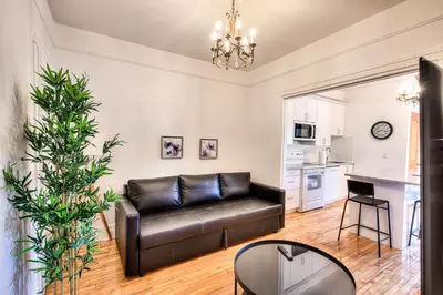a living room with a black leather couch and a kitchen at Montreal Vacation & Attractions Home by Downtown & Plateau in Montréal