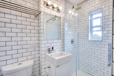 a white tiled bathroom with a toilet and a sink at Montreal Vacation & Attractions Home by Downtown & Plateau in Montréal