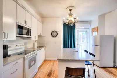 a kitchen with white cabinets and a counter top at Montreal Vacation & Attractions Home by Downtown & Plateau in Montréal