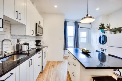 a kitchen with white cabinets and a black counter top at Montreal Vacation & Attractions Home by Downtown & Plateau in Montréal