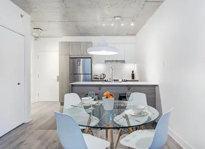 a dining room with a glass table and white chairs at Montreal rent in Montréal